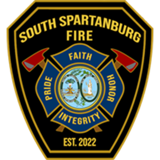 A black shield-shaped emblem with gold trim for South Spartanburg Fire. Two red fire axes cross behind a central circular blue emblem showcasing various images. Surrounding words read: "Pride," "Integrity," "Faith," and "Honor." Text below reads "Est. 2022.