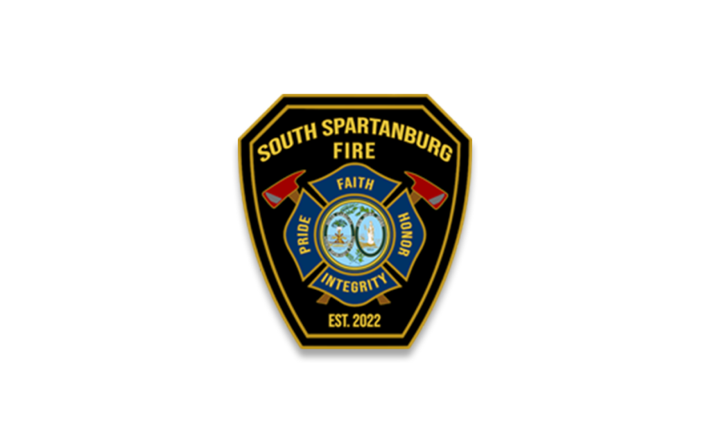 A badge for the South Spartanburg Fire Department. It features the words "Faith," "Pride," "Honor," and "Integrity," along with two crossed axes and a central seal depicting a fire symbol. The phrase "Est. 2022" is at the bottom.