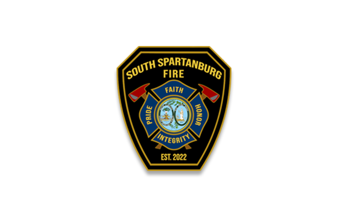 A badge for the South Spartanburg Fire Department. It features the words "Faith," "Pride," "Honor," and "Integrity," along with two crossed axes and a central seal depicting a fire symbol. The phrase "Est. 2022" is at the bottom.